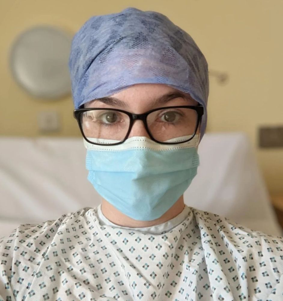 Laurene in a hospital gown, surgical cap and mask before one of her operations