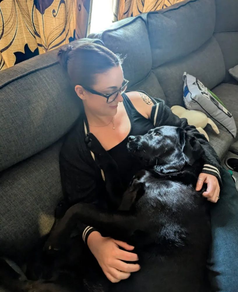 Laurene resting on the sofa at home with her dog Jess during her recovery